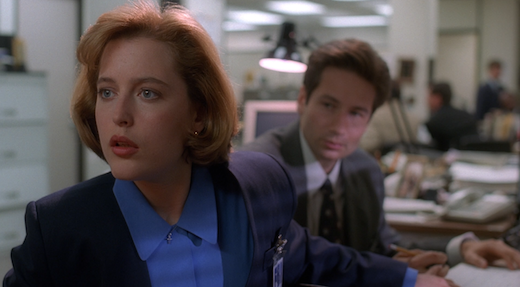 Scully reaches behind her to get Mulder's attention and inadvertanly tangles her fingers with his.