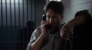 Mulder speaks to Scully on the phone from jail.