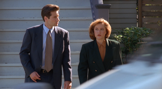Mulder and Scully walk away from Lauren's house, both looking irritated.