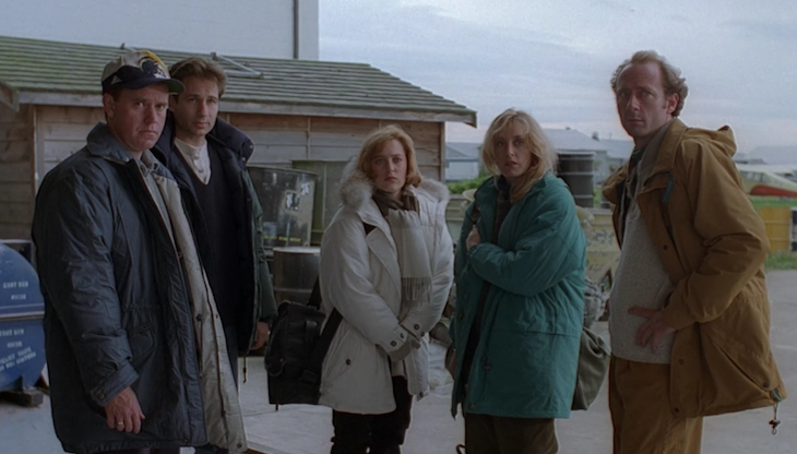 Mulder and Scully stand on an airfield base with the guest characters in the X-Files epsidode Ice.