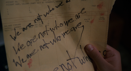 Mulder examines a piece of paper on which "We are not who we are" is feverishly scribbled several times.