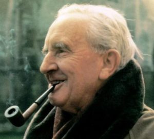 J.R.R. Tolkien smiles and smokes his pipe.
